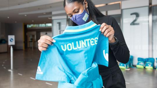Team London volunteer holding a blue volunteer t-shirt for Euro2020