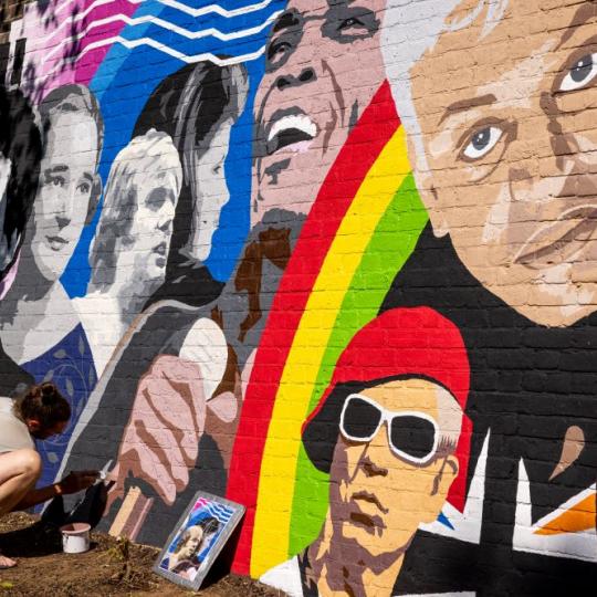 Artist working on a colourful mural showing iconic musicians from Croydon like Nadia Rose and Samuel Coleridge Taylor.   